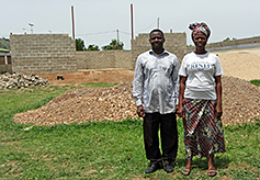 Pastor Philippe and his wife, Tchilalo, standing between the two structures