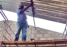 Pastor Moussa stands on scaffolding and attaches the sheet metal