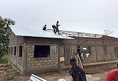 Workers carefully place the sheet metal roofing on the frame