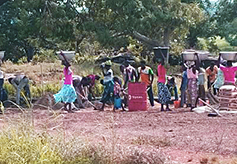 Women carry water for the bricks to the construction site